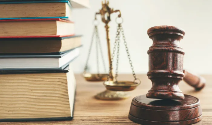 A gavel, scales of justice, and a stack of books on a table, representing the legal system.