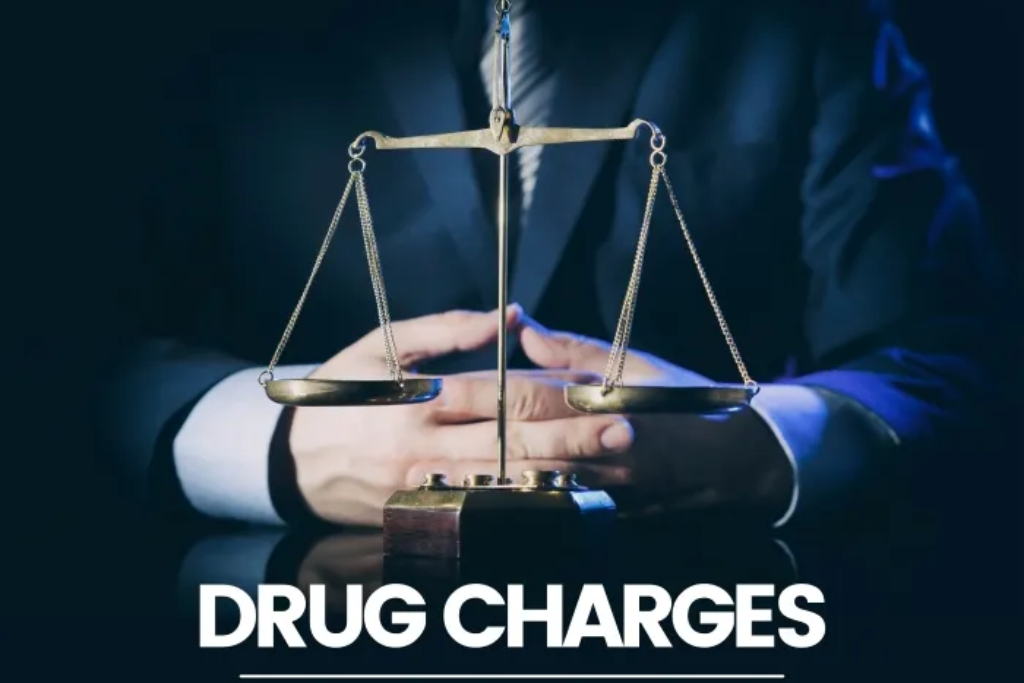 A scales of justice symbol positioned in front of a person in a suit, with the text "DRUG CHARGES" underneath.