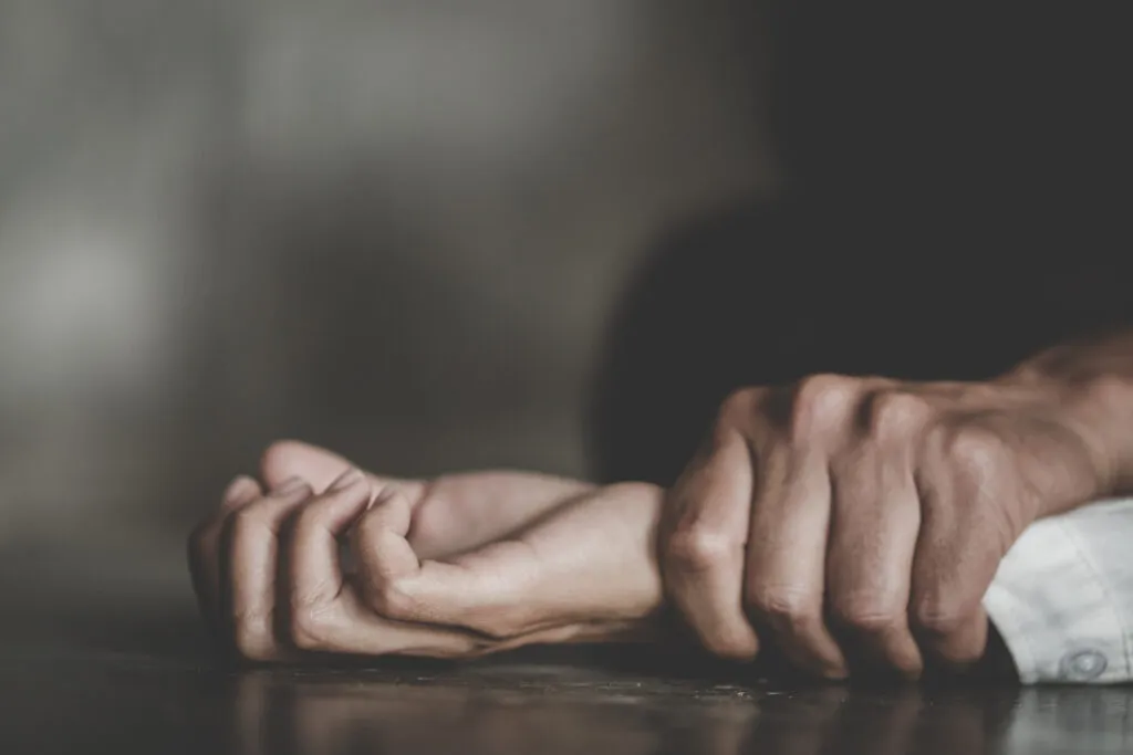 One hand firmly grasping another, suggesting a struggle or an act of violence.